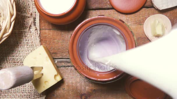 Slow motion milk being poured into an earthenware pot top view — Stock Video