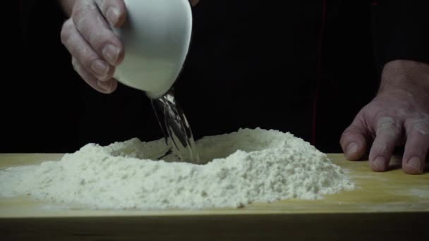 Koch gießt Wasser auf Mehl in Zeitlupe — Stockvideo