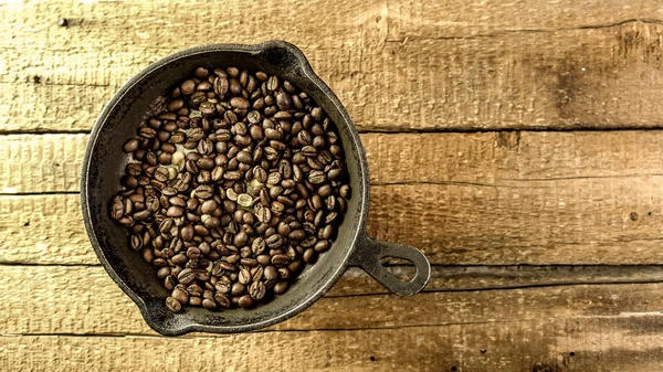 In a vintage frying pan, fried coffee beans — Stock Photo, Image