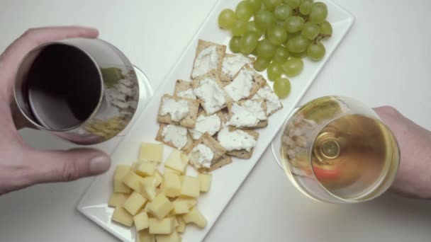 Twee glazen wijn, rood en wit, met snacks. Bovenaanzicht — Stockvideo