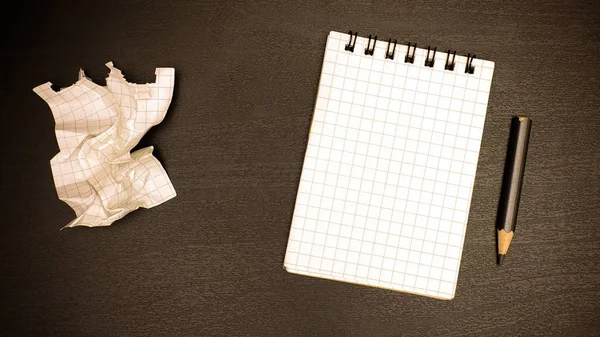 Sur la table du bureau il y a un cahier, un crayon et une feuille froissée — Photo