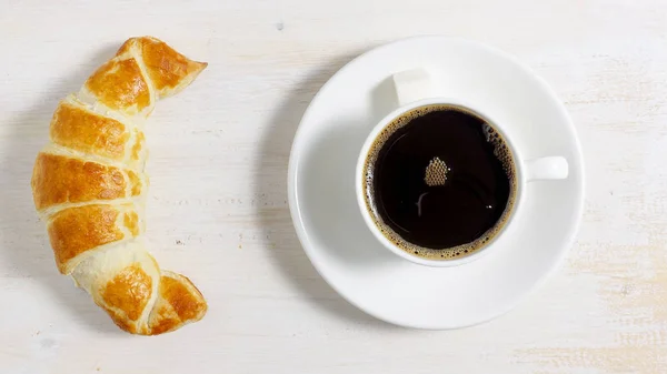 Croissant com uma xícara de café na mesa — Fotografia de Stock