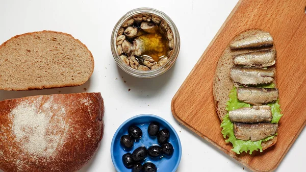 Sardine, spratti su un pezzo di pane nero con foglia di lattuga — Foto Stock