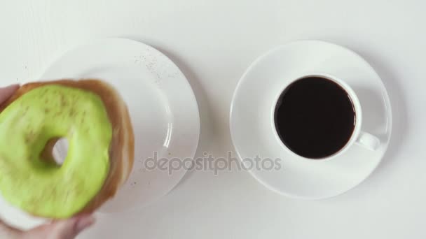 Eine weibliche Hand nimmt einen Donut und eine Tasse Kaffee, Draufsicht — Stockvideo