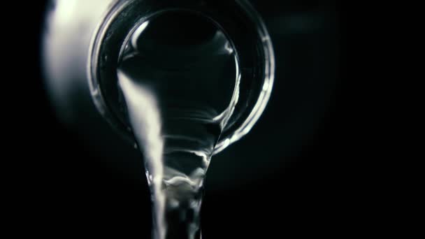 Vatten strömmar från en glasflaska, närbild, svart bakgrund, Slowmotion — Stockvideo