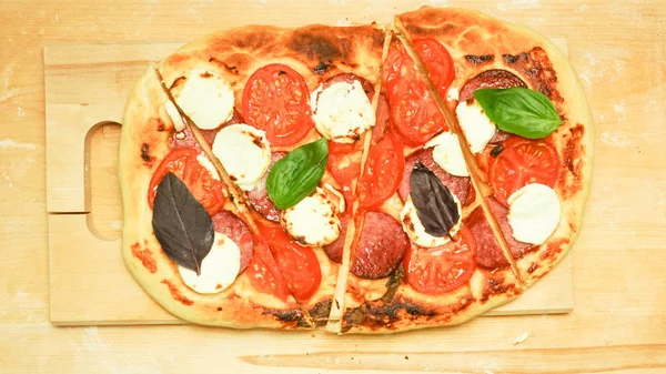 Pizza oval com queijo e salsichas, tomate e manjericão — Fotografia de Stock