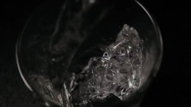 Ağır çekim. Siyah bir tabloda bir bardak su akar