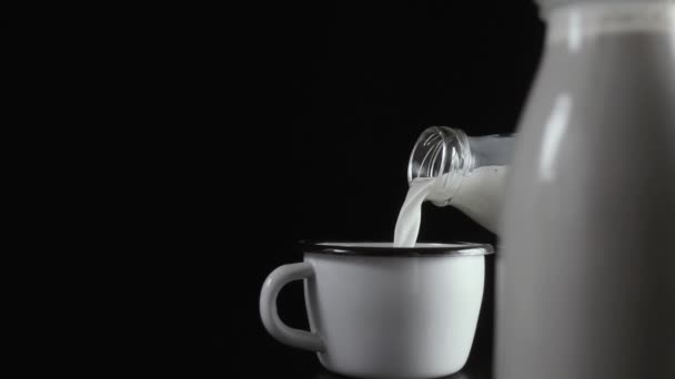 Milch aus einer Flasche ergießt sich in einen Becher. Zeitlupe — Stockvideo