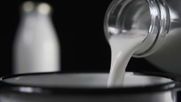 Au ralenti. Le lait d'une bouteille en verre est versé dans une tasse 