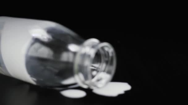 Slow-motion. Lege melk fles op een zwarte lijst met druppels — Stockvideo