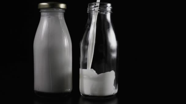 慢动作模式。在桌子上的两瓶。一瓶牛奶，填充第二个 — 图库视频影像