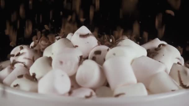 Marshmallow bestrooi met de geraspte chocolade op een zwarte achtergrond. Slow motion — Stockvideo