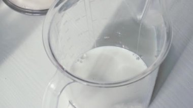 Ağır çekim. Süt süt ile ölçme kupa içine dökülür