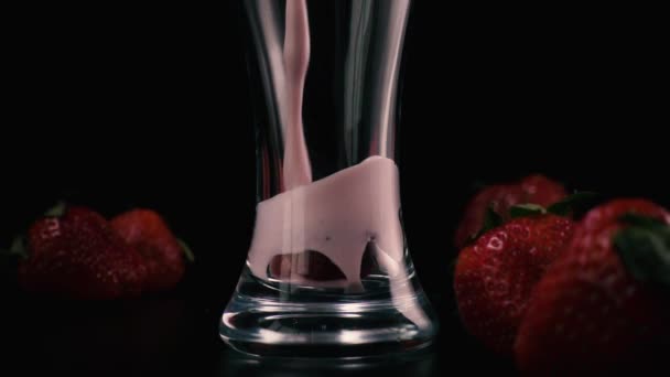 In a glass with strawberries pour a milkshake. Slow mo — Stock Video