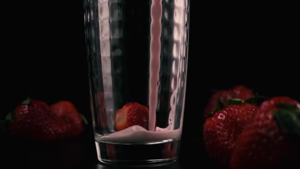 Медленное движение. Целая клубника в стакане с молочным коктейлем — стоковое видео