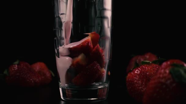 In ein Glas wird die geschnittene Erdbeere mit einem Cocktail gegossen. Zeitlupe — Stockvideo
