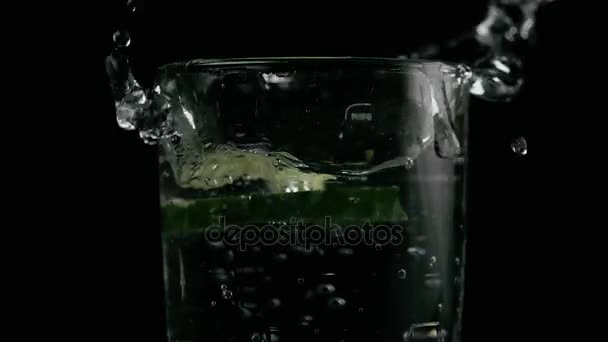 Slow mo. Two slices of cucumber fall into a glass — Stock Video