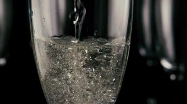 Bir bardak şampanya doldurur. Ağır çekim