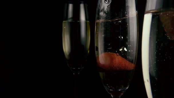 Jordgubbar falla i ett glas med champagne. Slow motion — Stockvideo