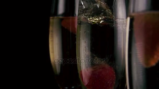 Slow mo. In eines der drei Gläser mit Champagner fallen Erdbeeren — Stockvideo