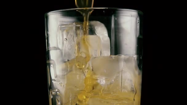 Une boisson coule dans le verre avec de la glace. Moteur lent 