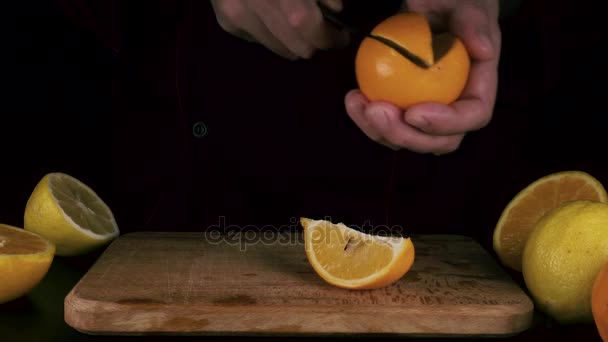 Man cuts a whole orange — Stock Video