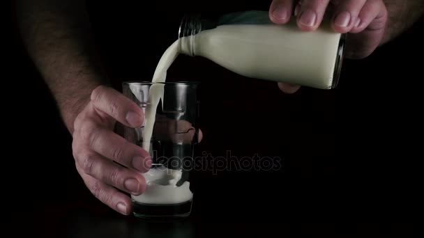 Медленно. Мужские руки наливают молоко в стакан — стоковое видео