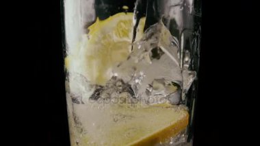 Ağır çekim. Buz ve limon ile bir bardak doldurmak