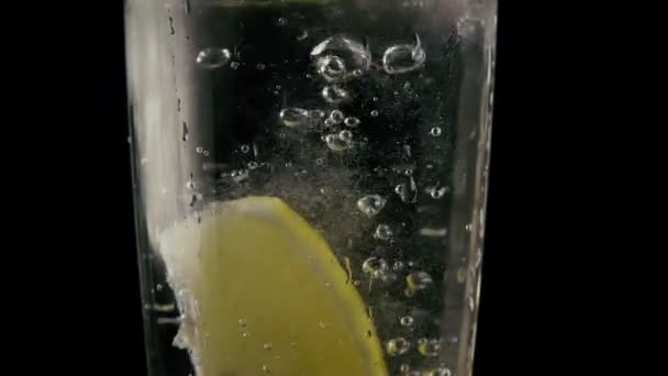In eine Limonade fällt eine Scheibe Zitrone. Langsames Wachstum — Stockvideo