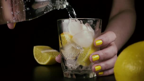 Le mani femminili da una bottiglia versano l'acqua in un bicchiere. Lento mo — Video Stock