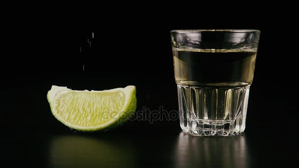 Zwolnionym PN. Plasterek limonki i kieliszek tequili na stole — Wideo stockowe