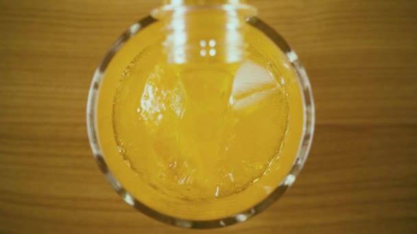 Um ein Glas aus einer Flasche mit einem orangefarbenen Drink von oben zu füllen. Langsames Wachstum — Stockvideo