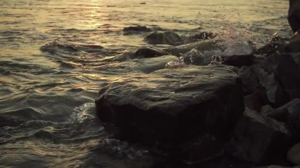 Splashes of water from a wave on a stony shore slow mo — Stock Video