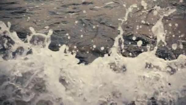 L'eau sombre crée une vague sur les rochers au ralenti 