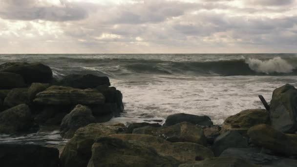 Des vagues de mousse roulent sur les rochers après une tempête — Video
