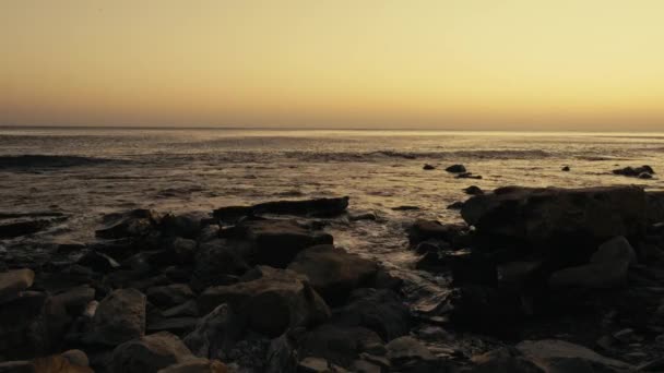 Pequeñas olas ruedan en tierra al atardecer — Vídeo de stock