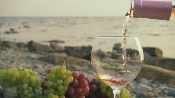 Медленное розовое вино наливается в стакан в море. — стоковое видео