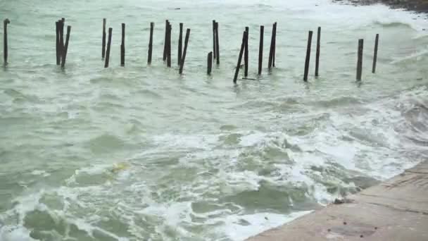 Ondas com lixo são quebradas em uma laje de concreto na costa — Vídeo de Stock