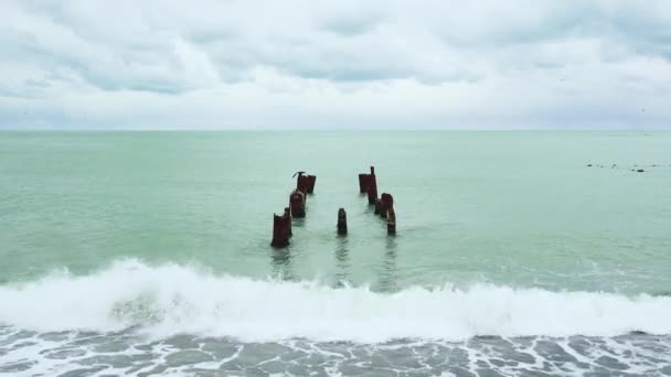 Sea surf and in the water the remains of the old pier — Stock Video