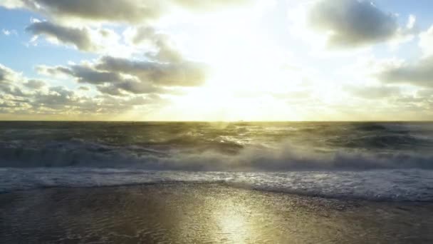 Die untergehende Sonne scheint durch die Wolken auf die stürmische See — Stockvideo