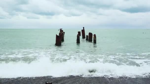 Surfen op de kust en de oude pier in het water — Stockvideo