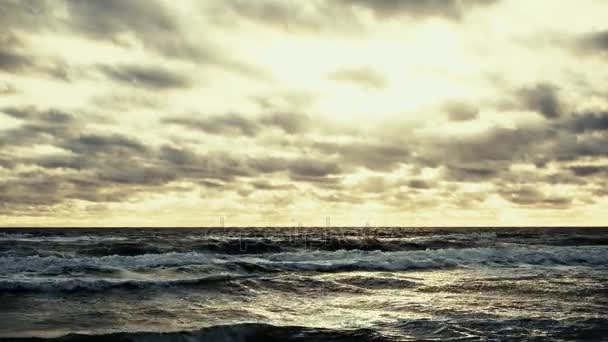 De ondergaande zon door de wolken verlicht de Oceaan — Stockvideo