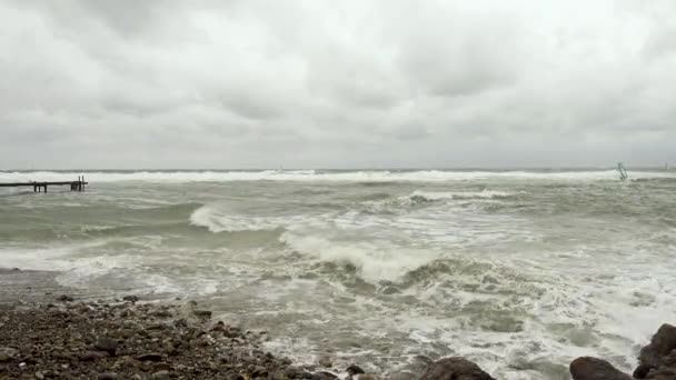 Muelle viejo a la izquierda y surfista a la derecha en la tormenta — Vídeo de stock