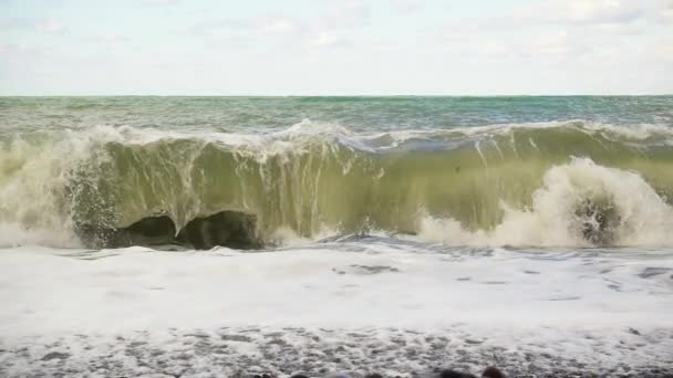 Eine große Welle bricht langsam über einen Kiesstrand. — Stockvideo