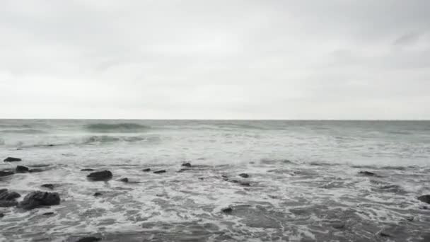 Морський скелястий пляж під хмарним небом — стокове відео