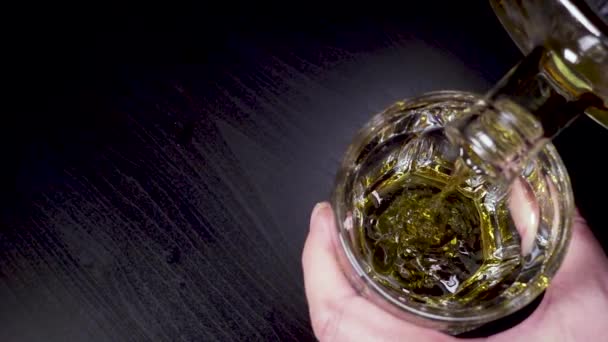 Медленный виски наливается в бокал с верхнего вида графина — стоковое видео