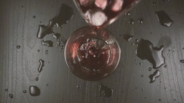 Vin rouge dilué avec de l'eau et de la glace est versé dans un verre 