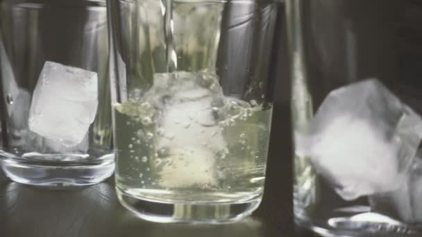 Na tabeli szklanki z kostkami lodu na czarnym tle zwolnionym tempie — Wideo stockowe
