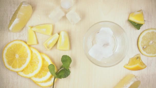 Cámara lenta en un vaso sobre una mesa rodeada de cascadas de hielo de limón — Vídeos de Stock