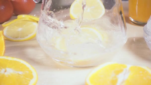 Slow motion soda pours into a decanter with lemon slices — Stock Video